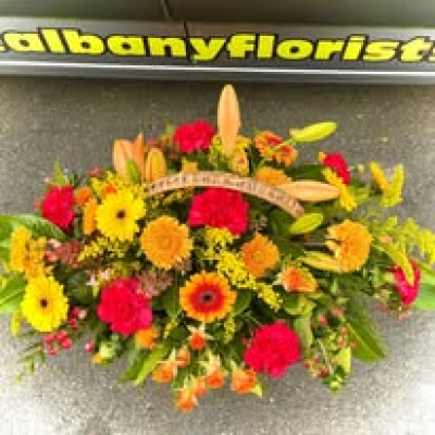 Autumn Glow - A vibrant and uplifting basket arrangement featuring a rich blend of warm golden, orange, red, and sunny yellow tones. Expertly designed with a natural, garden-inspired style, this display is filled with texture, movement, and seasonal charm. Its radiant colours create a heartfelt expression of warmth, remembrance, celebration, or gratitude, making it a beautiful choice for special occasions, thoughtful gestures, or commemorative tributes.